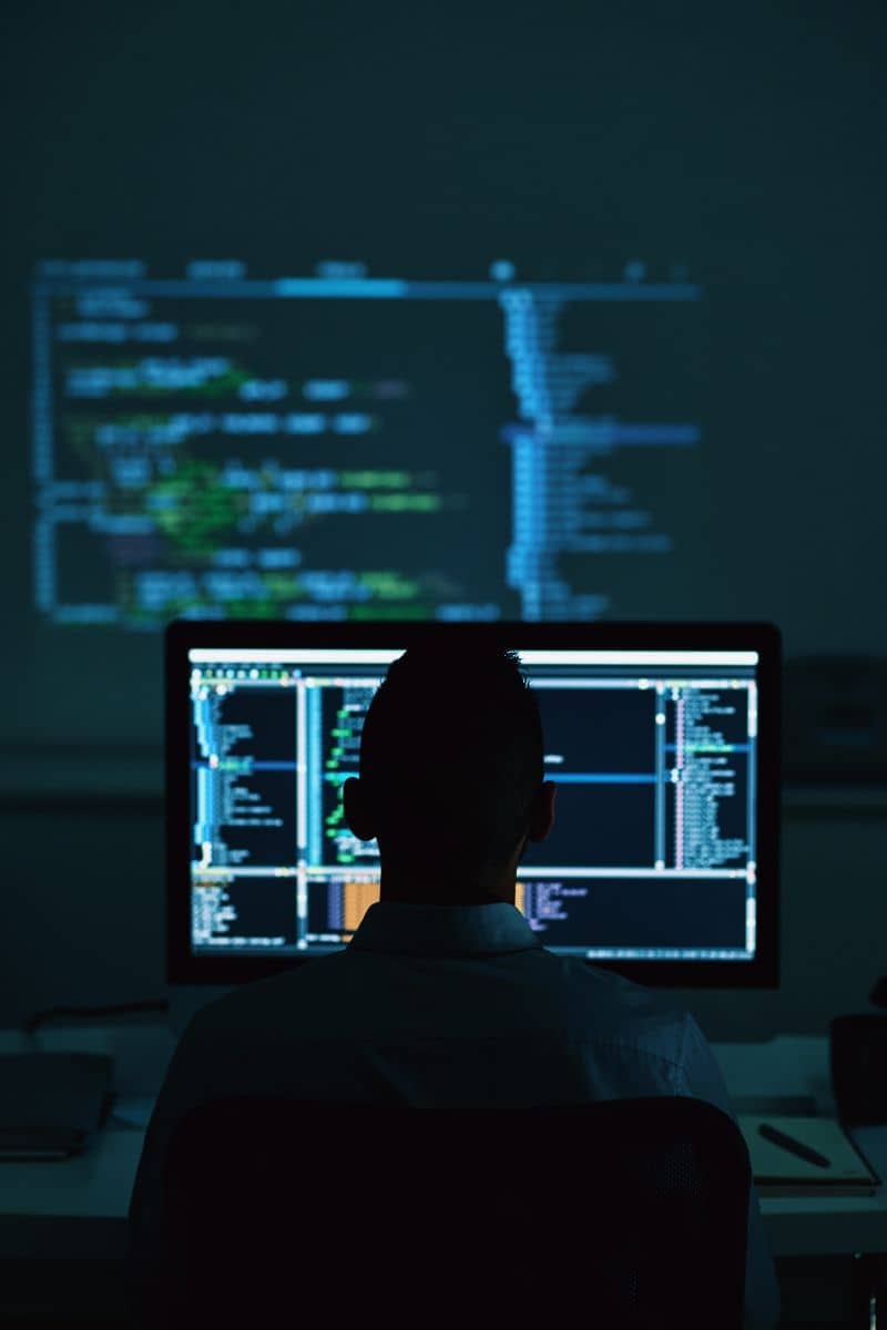 Our story section image - man sitting in front of computer screen in dark room
